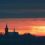 Kościół na tle różowo-pomarańczowego zachodu słońca.