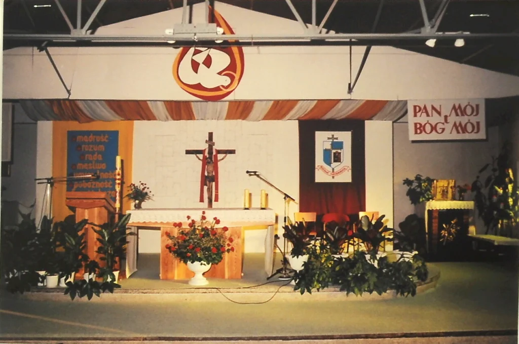 Wnętrze prowizorycznej kaplicy z&nbsp;ołtarzem, krzyżem i&nbsp;dekoracją liturgiczną